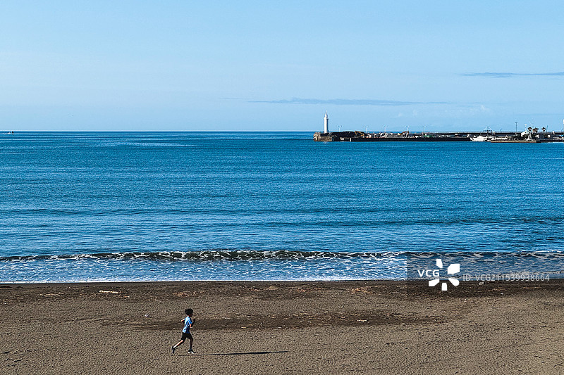 日本镰仓市七里滨海滩在海滩上奔跑的男孩的后视图图片素材