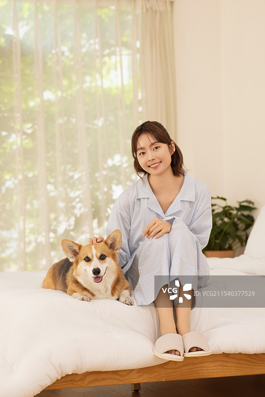 侧面视角的女人坐在床上与狗在一起图片素材