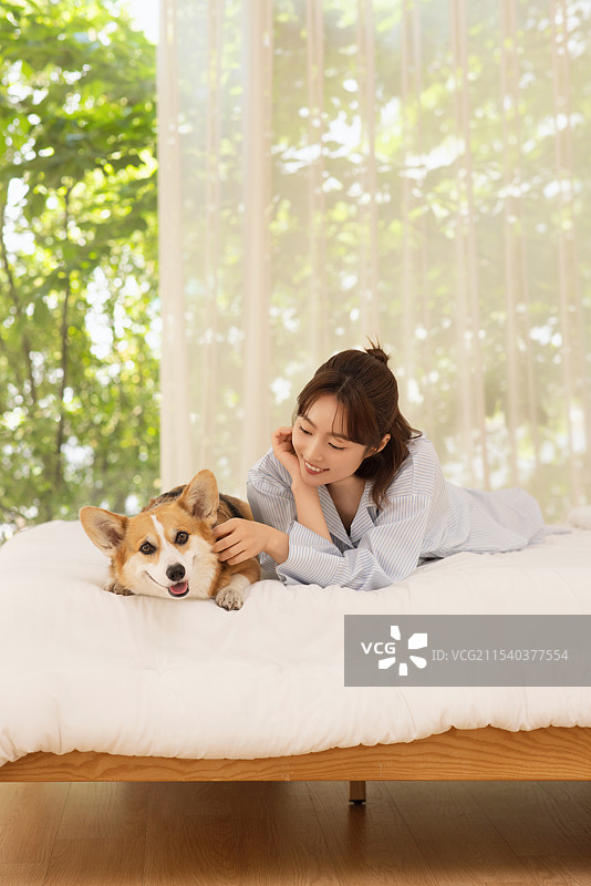 侧面视角的女人躺在床上与狗在一起图片素材