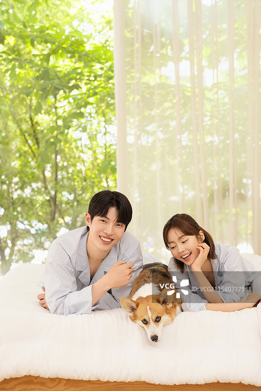 年轻情侣与狗躺在床上的肖像图片素材