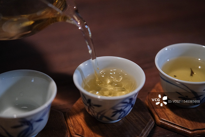功夫茶，茶水入杯。景德镇青花瓷茶杯。图片素材