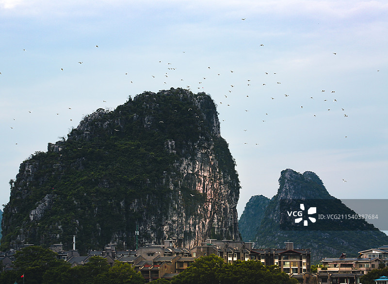 群鸟飞过山岩与村庄图片素材
