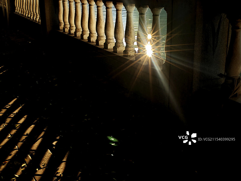 光影交错，岸边，阳光光穿越栏杆，倒影在路上，水面的阳光，投射在栏杆上，形成星芒，摄影师的视角，美无处图片素材