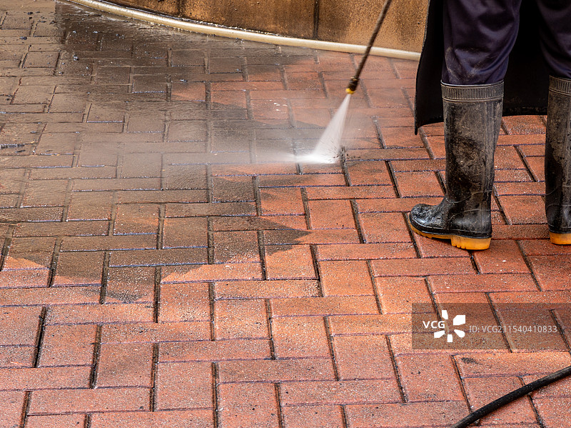 环卫工人使用强力喷射水流清洁砖砌路面图片素材