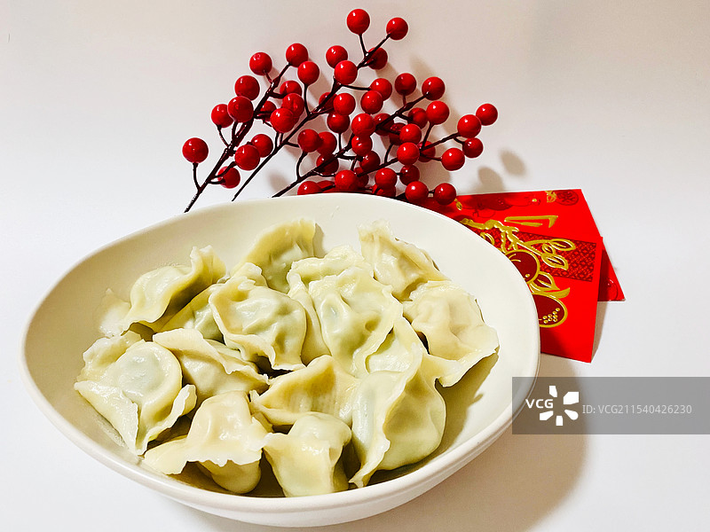 白色背景下饺子、红包、红果的特写图片素材