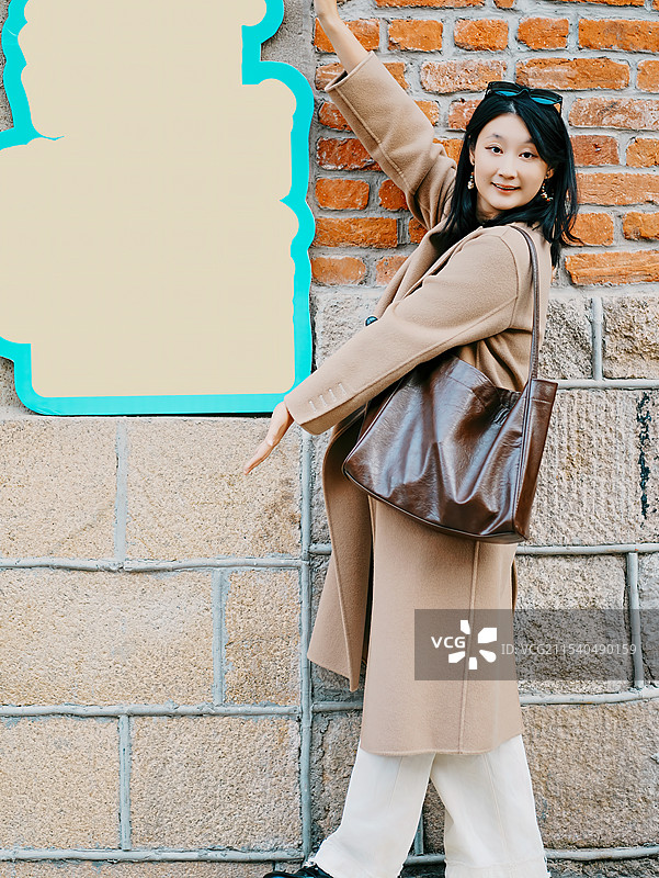 时尚的年轻女子靠着五颜六色的砖墙摆姿势图片素材