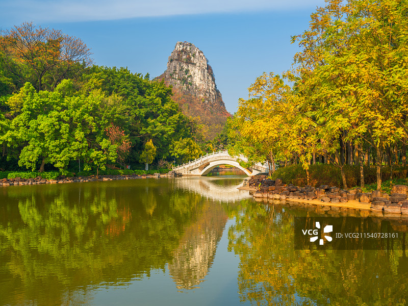 柳州马鹿山公园里白色的石拱桥、马鹿山、绿树林与宁静的湖面倒影共同构成了一幅宁静优美的风景画卷图片素材