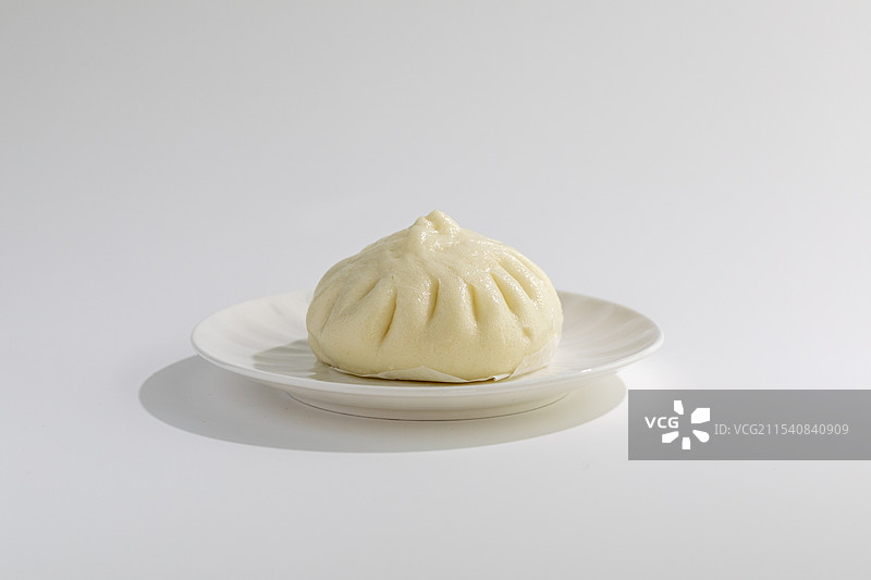 白色背景下盘子里肉包的特写镜头图片素材