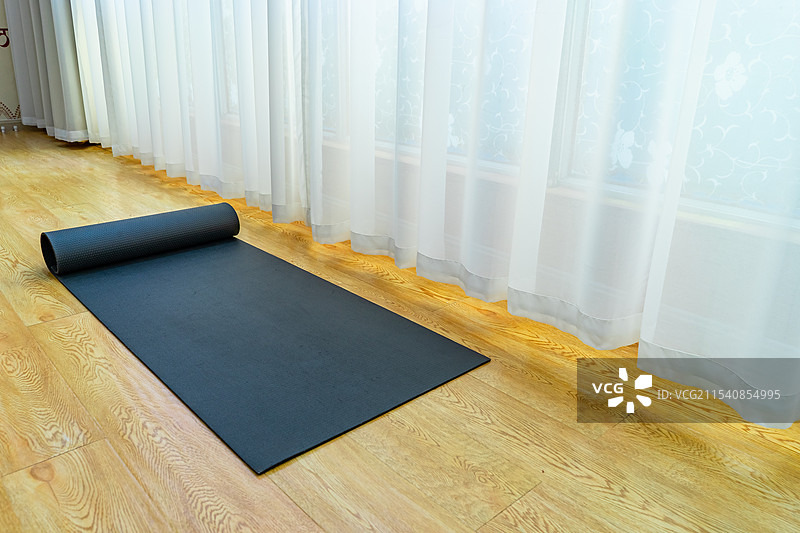 中国室内的瑜伽馆，木地板上的放置的黑色的展开的圆柱形瑜伽垫，室内无人图像摄影图片素材