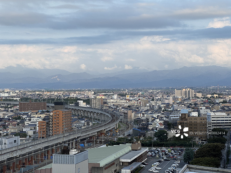 日本富山市多云天空下的立山山脉和北陆新干线高视角俯瞰城市全景图片素材
