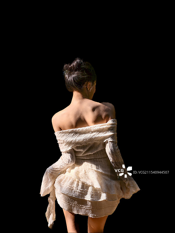 站在黑色背景下的妇女的后视图图片素材