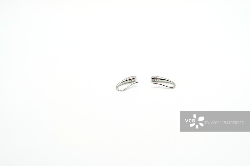 一对银色耳钉放在白色背景前图片素材