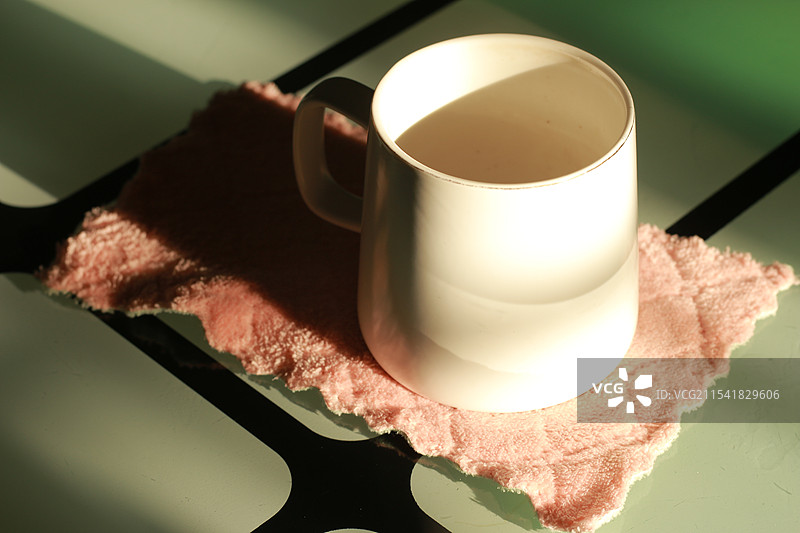 阳光照射在杯子上，杯子放在布上图片素材