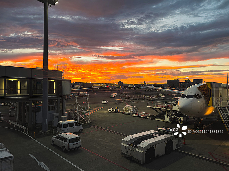 日落时的日本东京成田机场停机坪上正在装载货物的客机图片素材