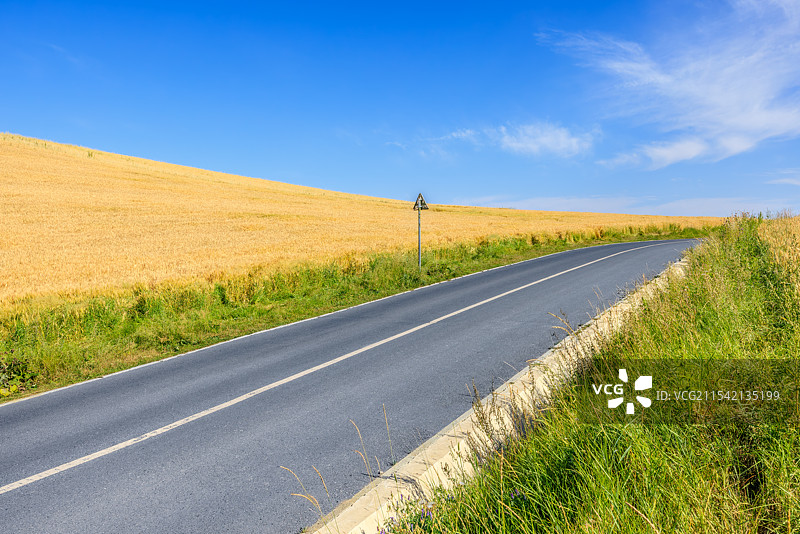 蓝天白云下通往田野的乡间公路图片素材