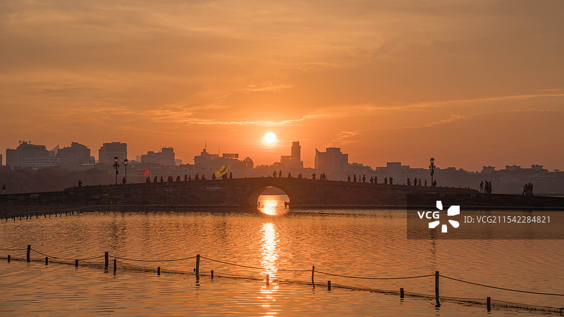 日出时分西湖白堤上阳光穿过桥洞图片素材