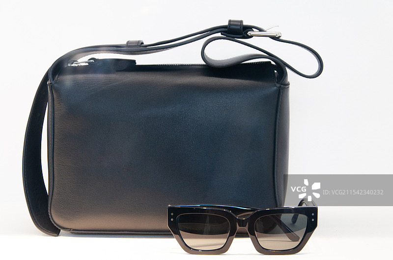 白色背景前的黑色皮包和眼镜图片素材