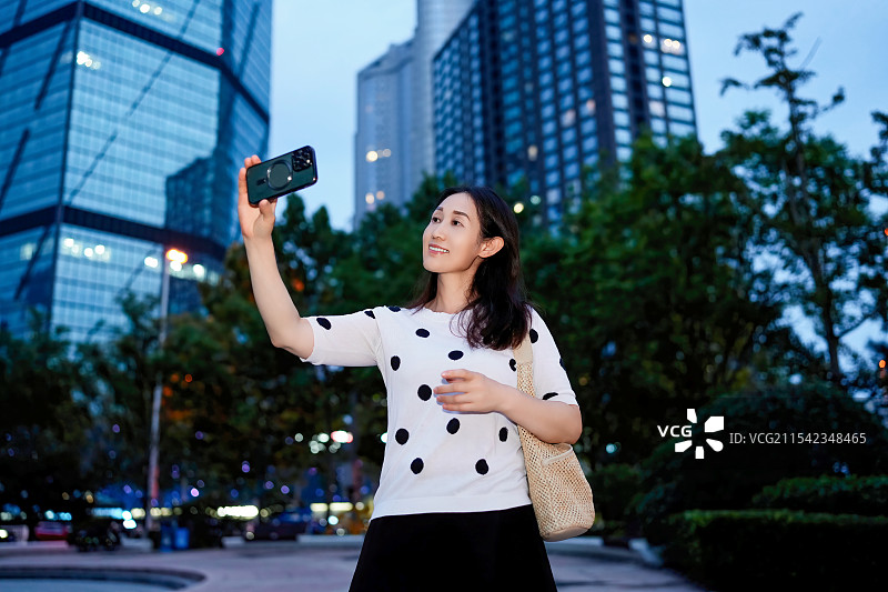 在城市中捕捉夜景自拍的女性图片素材