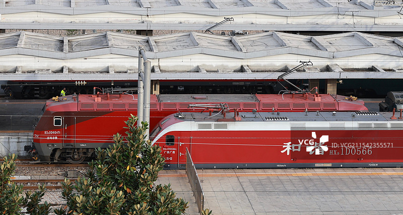 新式与旧式和谐号列车齐头并进在城市中图片素材