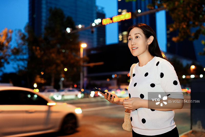 城市环境中的年轻女性在晚上用智能手机图片素材