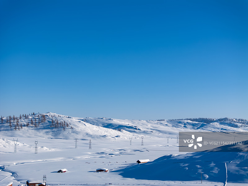 航拍新疆阿勒泰大雪覆盖的吉木乃草原石城雪山小木屋及输电线路铁塔图片素材