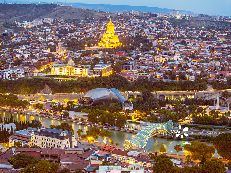 格鲁吉亚首都第比利斯夜幕降临，库拉河沿岸的圣三一大教堂、总统府、和平桥、音乐厅等地标建筑纷纷亮起灯光图片素材