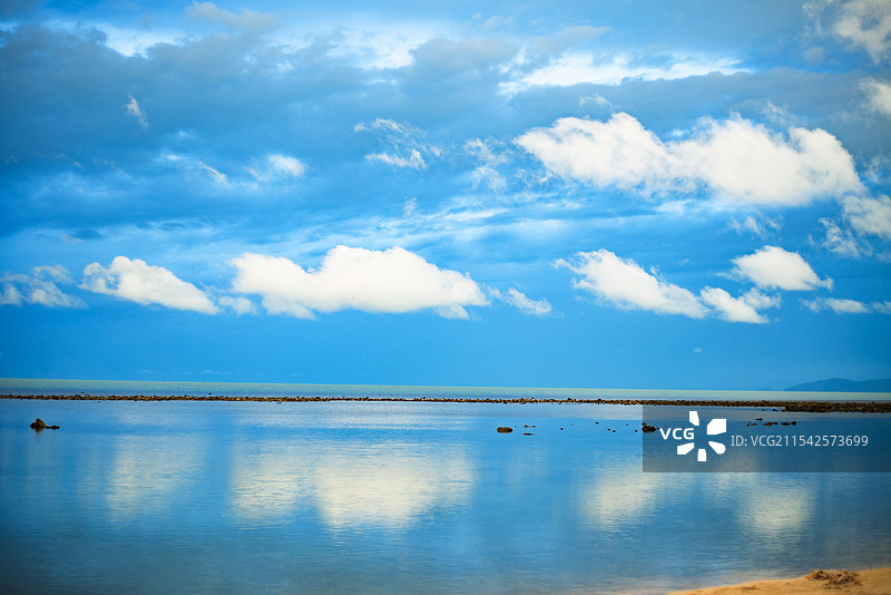 泰国苏梅岛宁静的海面，天空湛蓝，白云朵朵，倒映在清澈的海面上，岸边沙滩隐约可见，景色优美。图片素材