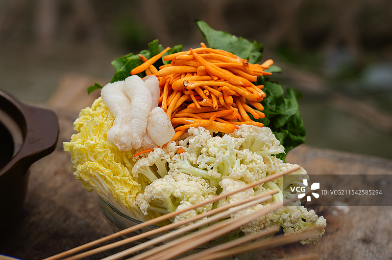 一个碗里装着多种食材，有白菜、菜花、胡萝卜丝等，旁边还有竹签，似为火锅食材。图片素材