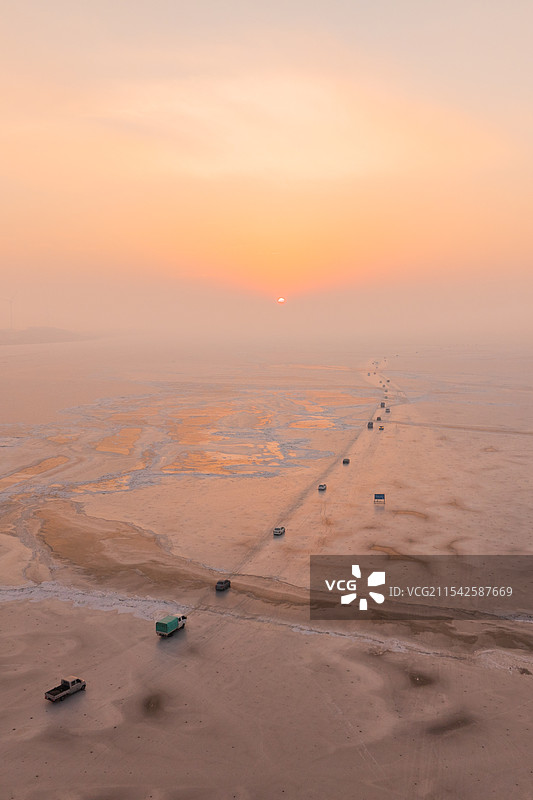 航拍冬季日出时行驶在冰封的吉林松原查干湖上的汽车车队图片素材