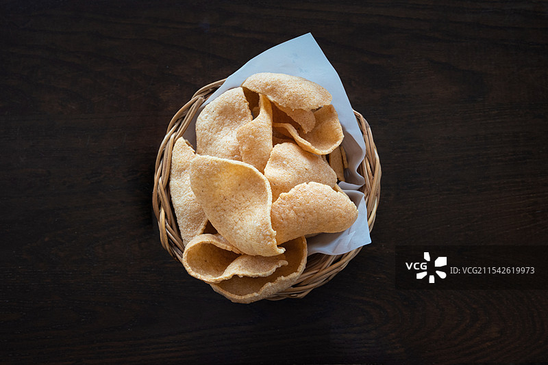 实木桌子上俯拍编织篮子中的泰式虾片高角度特写镜头图片素材