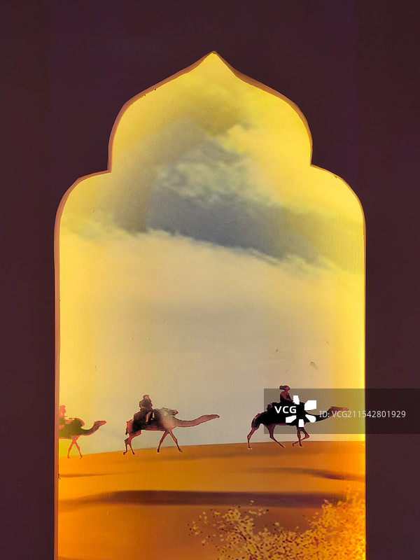 一个墙面造型的凹槽里，一副沙漠骆驼的画面在灯光下显得温暖、宁静图片素材