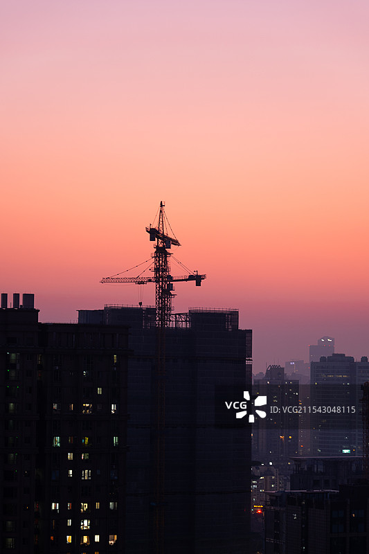 美霞下即将入夜的城市，高楼里已亮起点点灯光图片素材