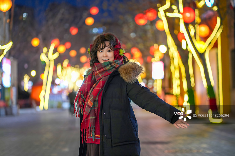 冬天的夜晚女人漫步在五颜六色的路灯下图片素材