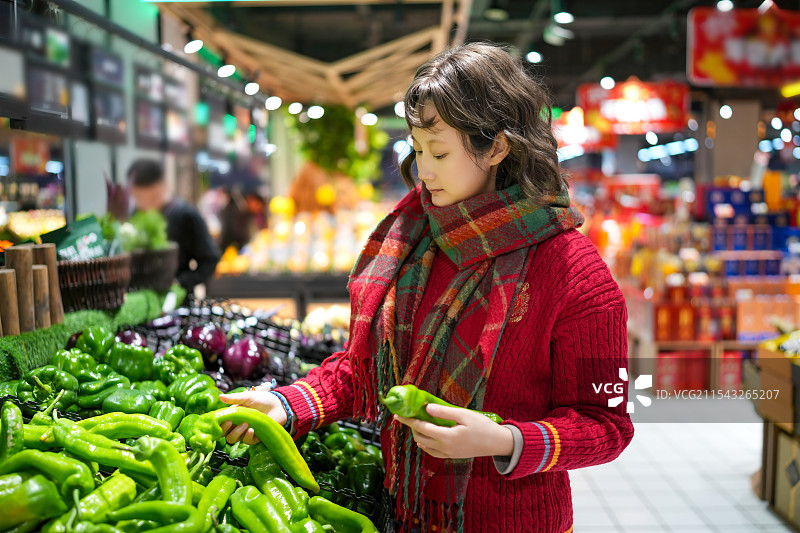 年轻女子在充满活力的杂货店挑选新鲜农产品图片素材