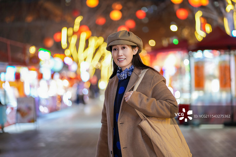 时尚的女人在节日的城市里享受冬夜漫步图片素材