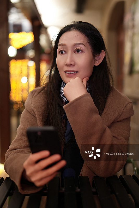 体贴的女人在舒适的咖啡馆与智能手机互动图片素材