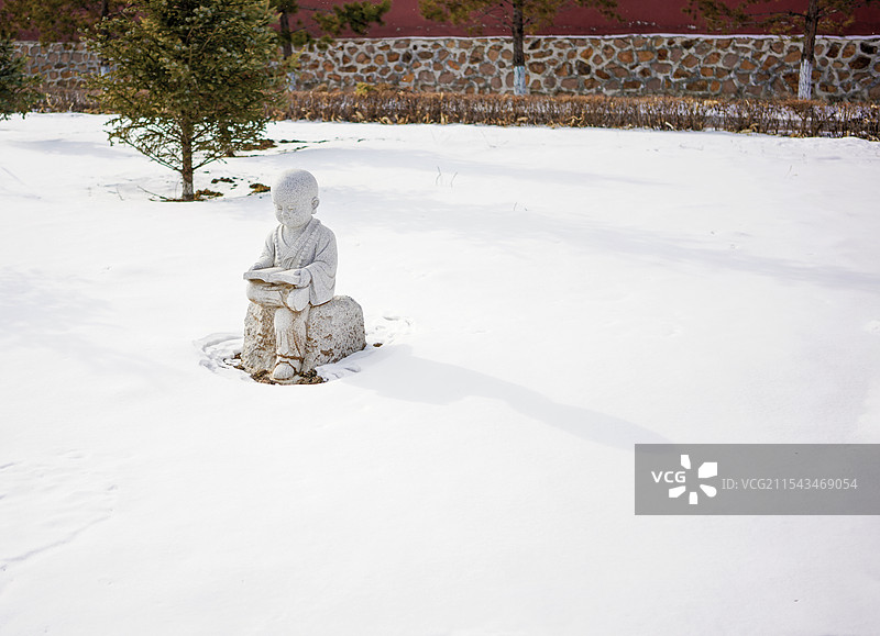 哈尔滨阿城区宝胜寺雪地里的沙弥读经文雕像图片素材