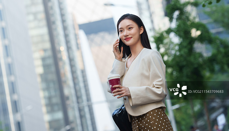 拿着咖啡的时尚青年女人打电话图片素材