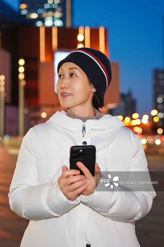 年轻女子在使用智能手机时享受城市夜生活图片素材