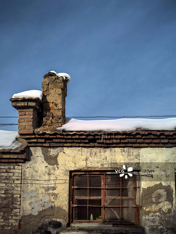 一间破旧的平房上，落满白雪，斑驳的墙面和陈旧的木窗，讲述着岁月的沧桑图片素材