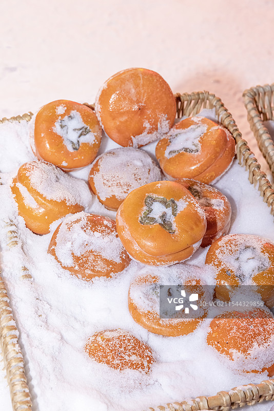 冬天雪里的金黄色的磨盘大冻柿子图片素材