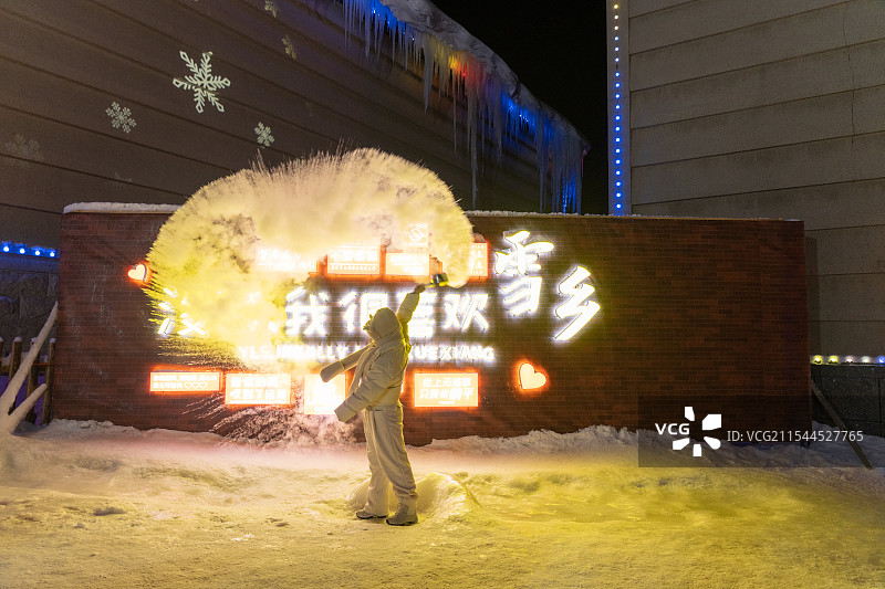 东北雪乡冬季特色娱乐项目，一个人在寒冷的灯光下泼水成冰图片素材