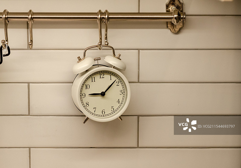 白色瓷砖墙壁上挂着一个白色钟表图片素材