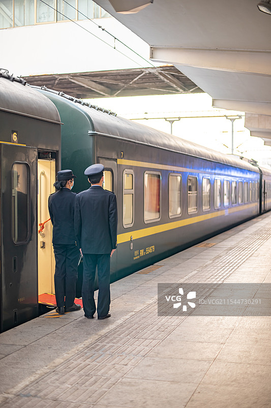 中国国内火车交通公共设施，泰安火车站传统复古绿皮火车月台站着两个工作人员，户外白昼图像摄影图片素材