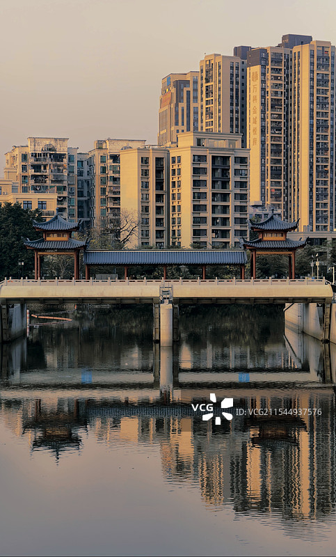夕阳下，古桥横跨水面，亭台楼阁飞檐翘角，尽显古韵悠长。桥的那头，是鳞次栉比的现代高楼，在余晖中闪耀着图片素材