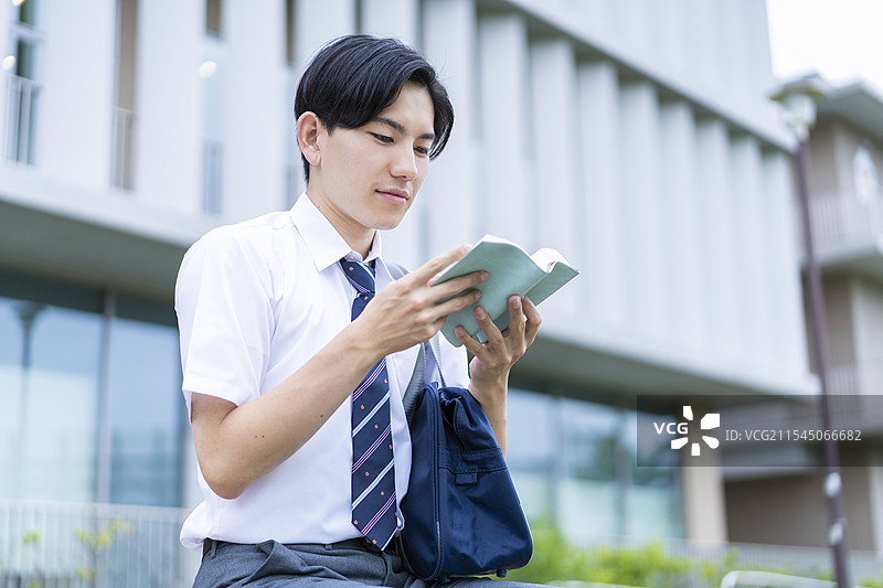 高中男孩在阅读一本书图片素材