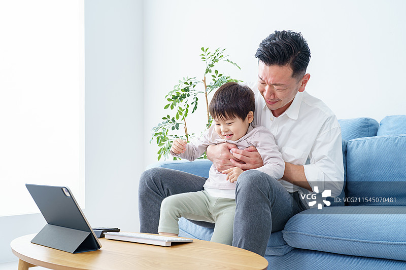 孩子打断正在远程工作的父亲图片素材