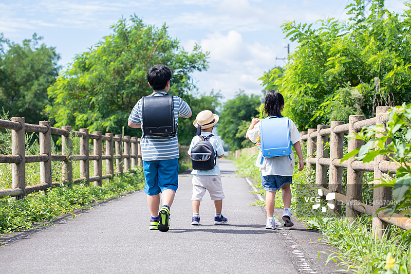 小学和幼儿园的孩子们，兄弟姐妹和三兄弟在路上走。图片素材