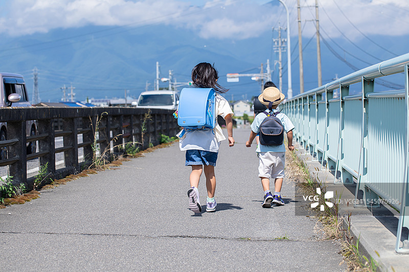 小学和幼儿园的孩子们，兄弟姐妹和三兄弟姐妹在路上走。图片素材