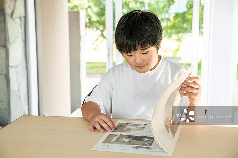 小学生男孩在桌子上看杂志图片素材